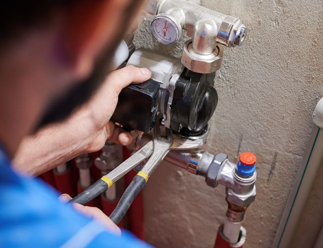 male plumber installing heating radiator in apartment.